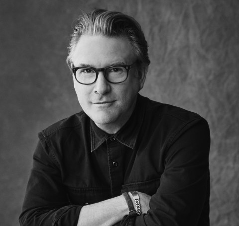 black and white image of a man in glasses sitting on chair